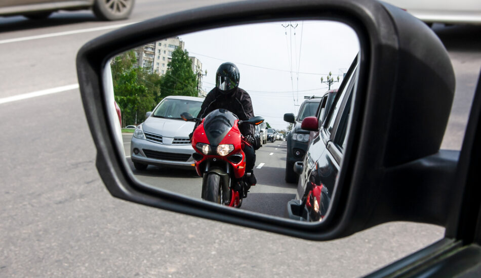 Motorrijders in de zijspiegel van een auto.