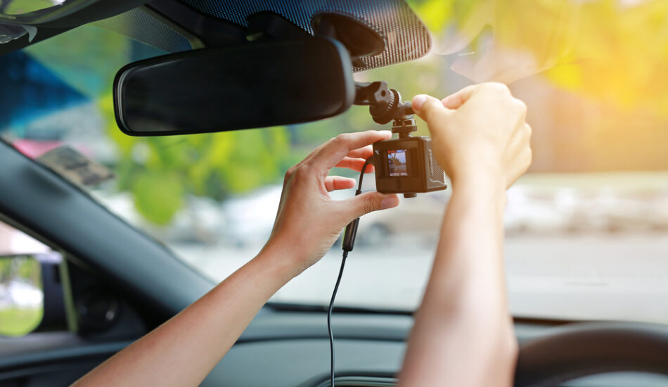 Iemand installeert zijn dashcam in de auto.