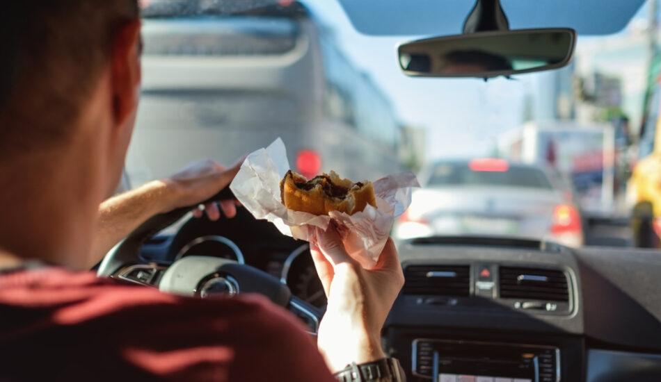 Man is aan het eten achter het stuur. In welke landen is dat verboden?