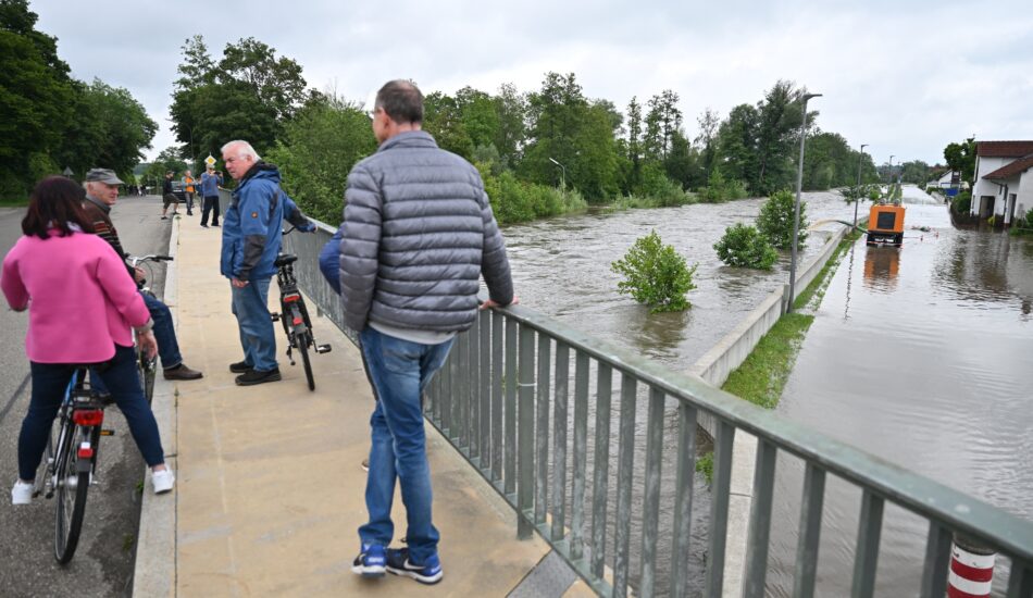 Fietsers kijken naar de overstromingen in Duitsland.